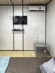 una camera con letto e TV a parete di Padang Besar Rainbow Cabin Homestay a Padang Besar