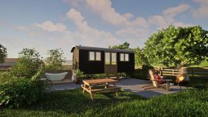 a person sitting on a bench next to a tiny house at Silver Fern Glamping in Aberystwyth