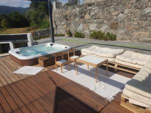 a hot tub on a deck with a couch and a table at Gerês VillaCella in Vieira do Minho