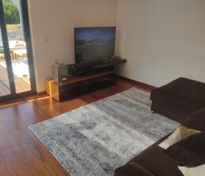 a living room with a flat screen tv and a rug at Gerês VillaCella in Vieira do Minho