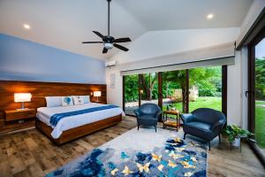 1 dormitorio con 1 cama y 2 sillas en Luxury Vacation Rentals At Hacienda Pinilla, en Tamarindo