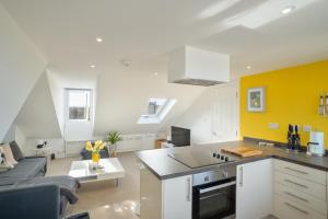 Stylish Herne Bay apartment by the sea في Kent: مطبخ وغرفة معيشة بها صفراء وبيضاء