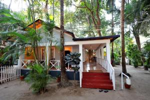 uma casa com uma escada vermelha no meio das árvores em Temple Garden Seaside Cottages em Palolem