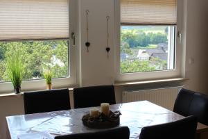 a dining room with a table and two windows at Ferienwohnung Am Sonnenhang Blecher in Bad Laasphe