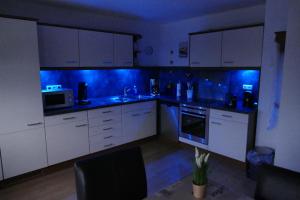 een keuken met witte kasten en blauwe verlichting bij Ferienwohnung Am Sonnenhang Blecher in Bad Laasphe