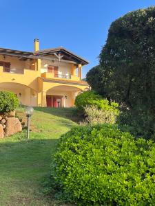 奇亚La Casa sulla collina "Baccu e Idda"的前面有灌木丛的大黄房子