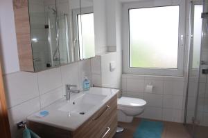 een badkamer met een wastafel, een toilet en een raam bij Ferienwohnung Am Sonnenhang Blecher in Bad Laasphe