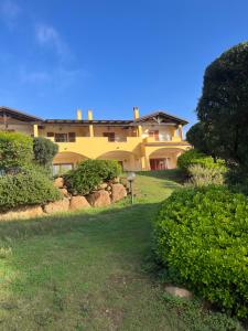 奇亚La Casa sulla collina "Baccu e Idda"的一座大黄房子,位于一座灌木丛的小山上