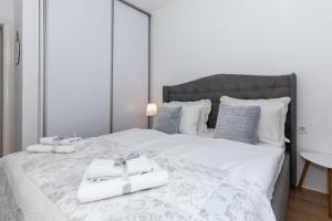 ein weißes Bett mit zwei weißen Handtüchern darauf in der Unterkunft Happy Apartment II in Mostar