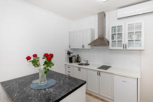 eine weiße Küche mit einer Vase aus Rosen auf der Theke in der Unterkunft Happy Apartment II in Mostar