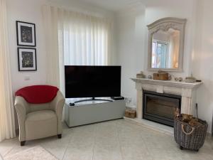 sala de estar con TV, silla y chimenea en Villa Karon en Almancil