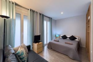 1 dormitorio con cama, sofá y TV en ApartEasy - Gracia Apartments, en Barcelona