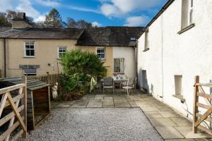 a patio with a table and chairs in front of a house at Pinewood Cottage - Newby Bridge in Lakeside