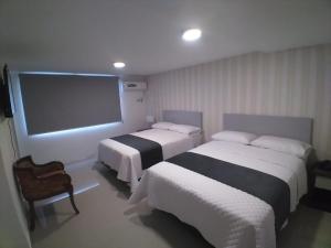 Habitación de hotel con 2 camas y TV de pantalla plana. en Hotel Ejecutivo Portoviejo, en Portoviejo