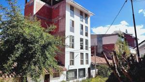 un edificio blanco y rojo junto a un árbol en Apartamento en Cusco II, en Cusco 8 fotos más