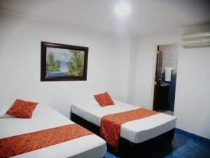 Gran Hotel Cali في كالي: غرفة بسريرين وصورة على الحائط