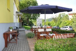 patio ze stołami, krzesłami i parasolem w obiekcie Hotel Wolke w mieście Meiningen