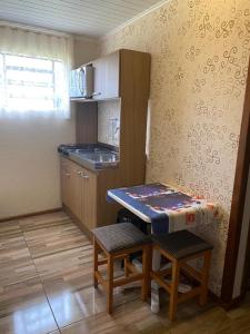 a small kitchen with a table and two stools in it at RESIDENCIAL BORGES CANELA in Canela