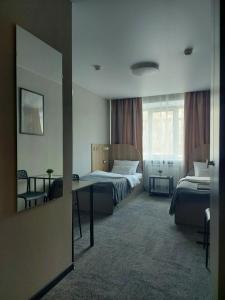チェリャビンスクにあるAstraのベッド2台、テーブル、窓が備わるホテルルームです。