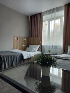 Un dormitorio con 2 camas y una mesa de cristal con una planta en Astra, en Chelyabinsk