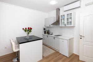 eine Küche mit weißen Schränken und einer schwarzen Arbeitsplatte in der Unterkunft Happy Apartment II in Mostar