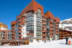 a building with people standing in the snow in front of it at Les appartements de Makalu Val Thorens in Val Thorens