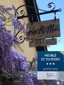 un cartel que dice kermit café en un edificio con flores púrpuras en Gîte Ke'R Maé, en Le Quiou