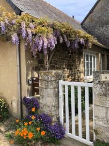 una casa con una valla blanca y flores púrpuras en Gîte Ke'R Maé, en Le Quiou