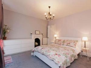 a white bedroom with a bed and a fireplace at Harbour View in Kingswear