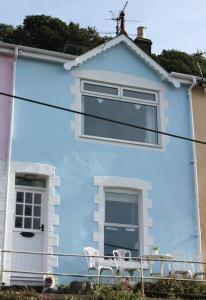 una casa azul con dos sillas delante en Harbour View en Kingswear