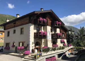 a building with flowers on the balconies of it at Hotel Garni Rin Da Rin in Livigno