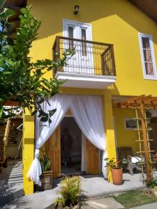 una casa amarilla con una cortina blanca sobre la puerta en Vila Sabará en Pinheira