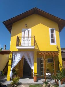 uma casa amarela com uma varanda em Vila Sabará em Pinheira