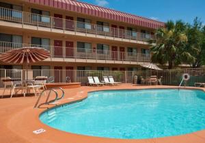 una piscina frente a un hotel con sillas y sombrilla en Red Roof Inn Corpus Christi South, en Corpus Christi