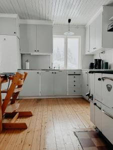 cocina con armarios blancos y suelo de madera en Charming house with wood stove near lake, en Virserum