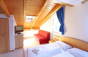małą sypialnię z łóżkiem i czerwonym krzesłem w obiekcie Residence Sonneck w mieście Martell