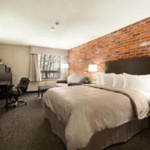 Habitación de hotel con cama grande y pared de ladrillo en Super 8 by Wyndham Timmins ON, en Timmins