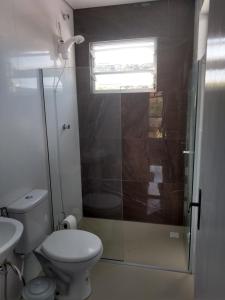 a bathroom with a toilet and a glass shower at Vila Sabará in Pinheira