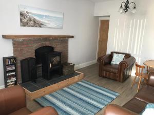 a living room with a brick fireplace and a chair at Curlew Cottage and Sunset View 