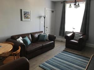 a living room with a brown couch and a table at Curlew Cottage and Sunset View 