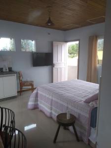 a bedroom with a bed and a table and a kitchen at Vila Sabará in Pinheira
