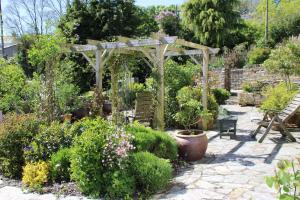 a garden with a wooden pergola and some plants at May House A beautiful Cornish holiday home in the heart of Cornwall in Wadebridge