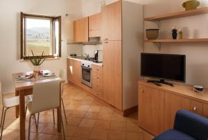 uma pequena cozinha com uma mesa e uma televisão num quarto em SeiPetali em Cannara