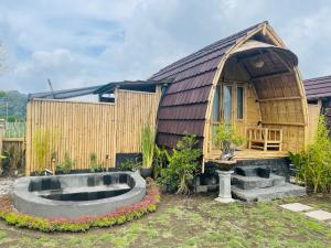 Tegal Bamboo cottages & private hot spring في Baturaja: منزل صغير أمامه حوض كبير