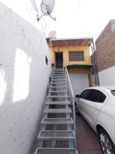una escalera que conduce a un edificio con un coche blanco en Departamento Elida en San Rafael