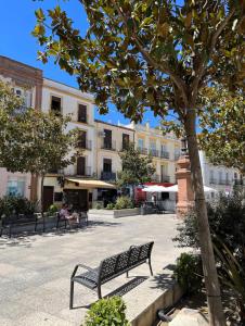a park bench next to a tree and buildings at Rondabella 3 Parking Gratis Centro in Ronda