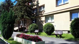 dwie ławki przed budynkiem z kwiatami w obiekcie Hotel Skaut w mieście Chorzów