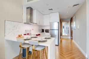 a kitchen with white cabinets and a counter with stools at Luxury Apt - Rooftop Pool - City View in Dubai