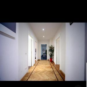- un couloir avec des murs blancs et du parquet dans l'établissement Central Hostel Milano, à Milan