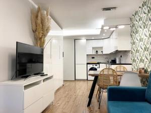 een woonkamer met een tv en een tafel met stoelen bij Apartament Marina Hel in Hel